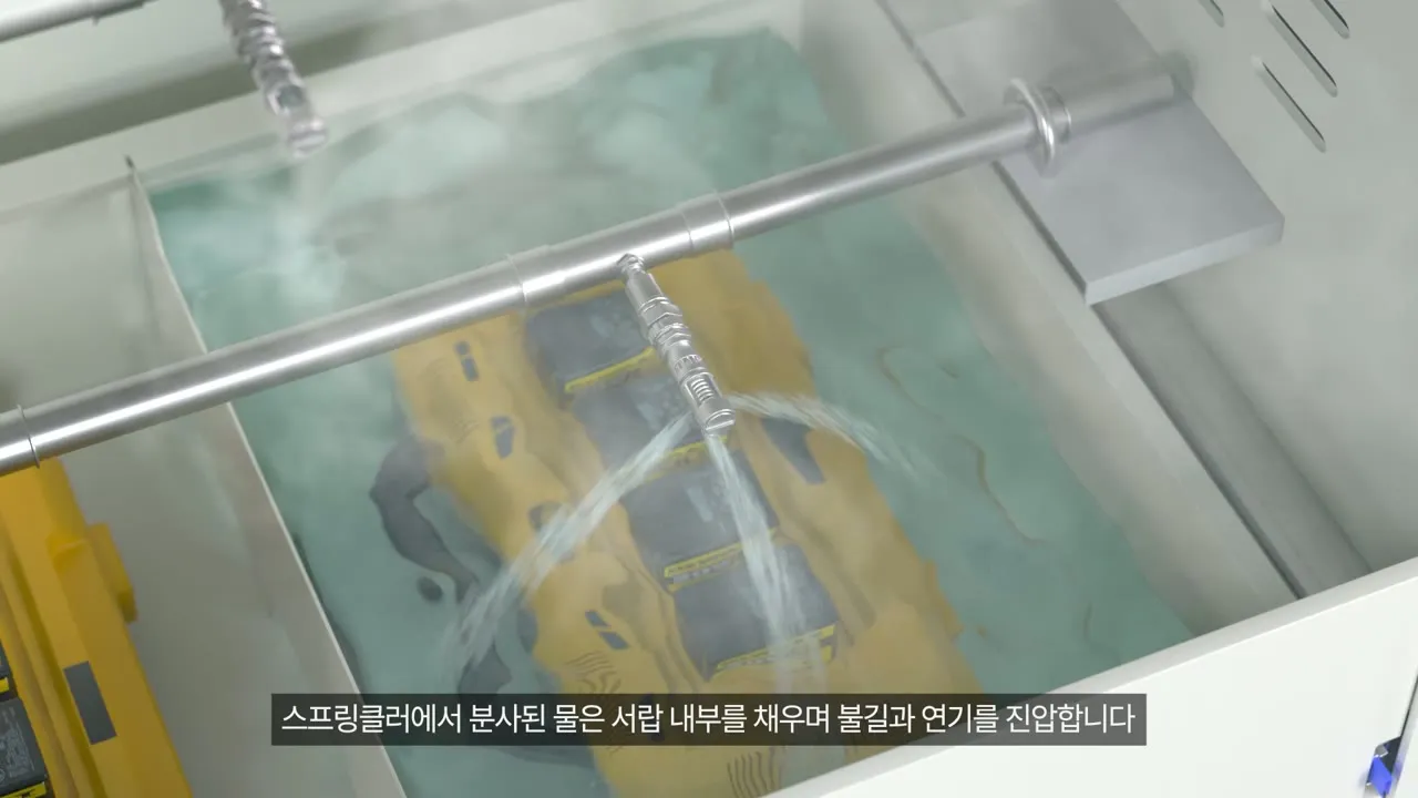 배터리 보관함 영상의 장면. 스프링클러에서 나온 물이 서랍을 채워 노란 배터리 팩의 불길과 연기를 잡는다