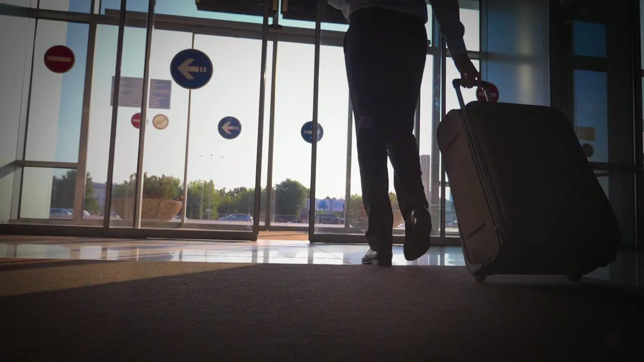 반도체 칩 기술 소개 영상의 실사 스톡 영상 장면. 공항 출입문 앞에서 캐리어를 끄는 사람의 뒷모습